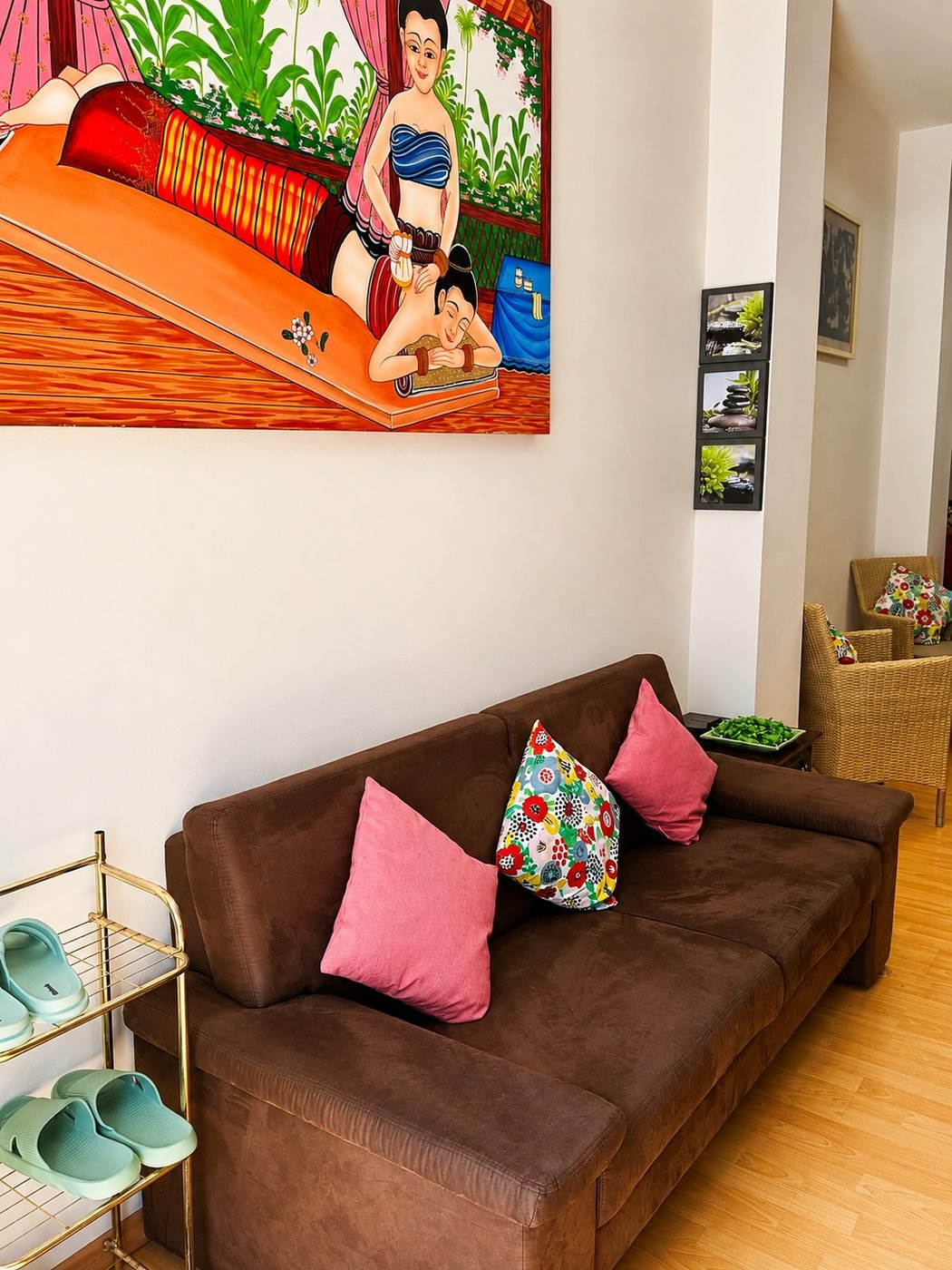 Wartebereich mit Sofa, thailändischem Wandbild und bereitgelegten Hausschuhen